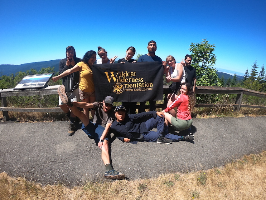 Photo of a group of students holding a WWO banner on a paved trail