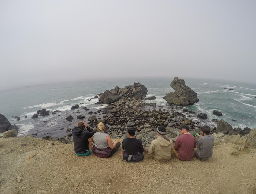 Photo of students sitting on a cliff overlooking the ocean
