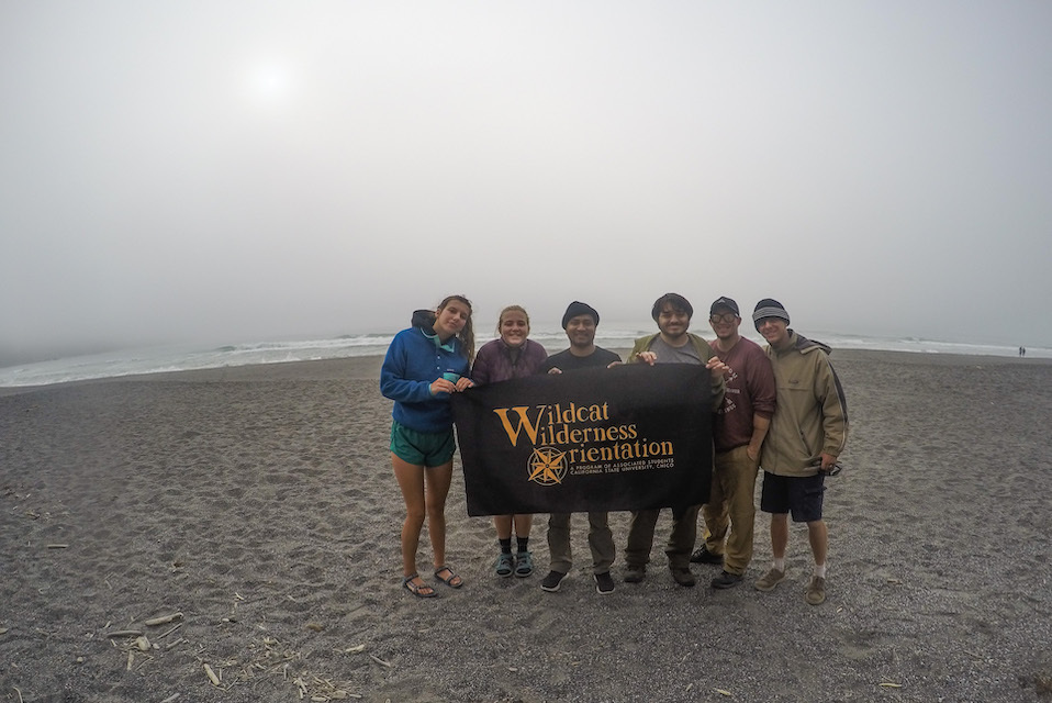 Photo of students holding a WWO banner on a beach