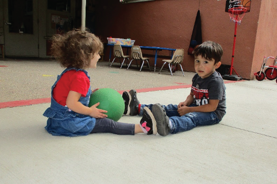 Photo of two children rolling a ball