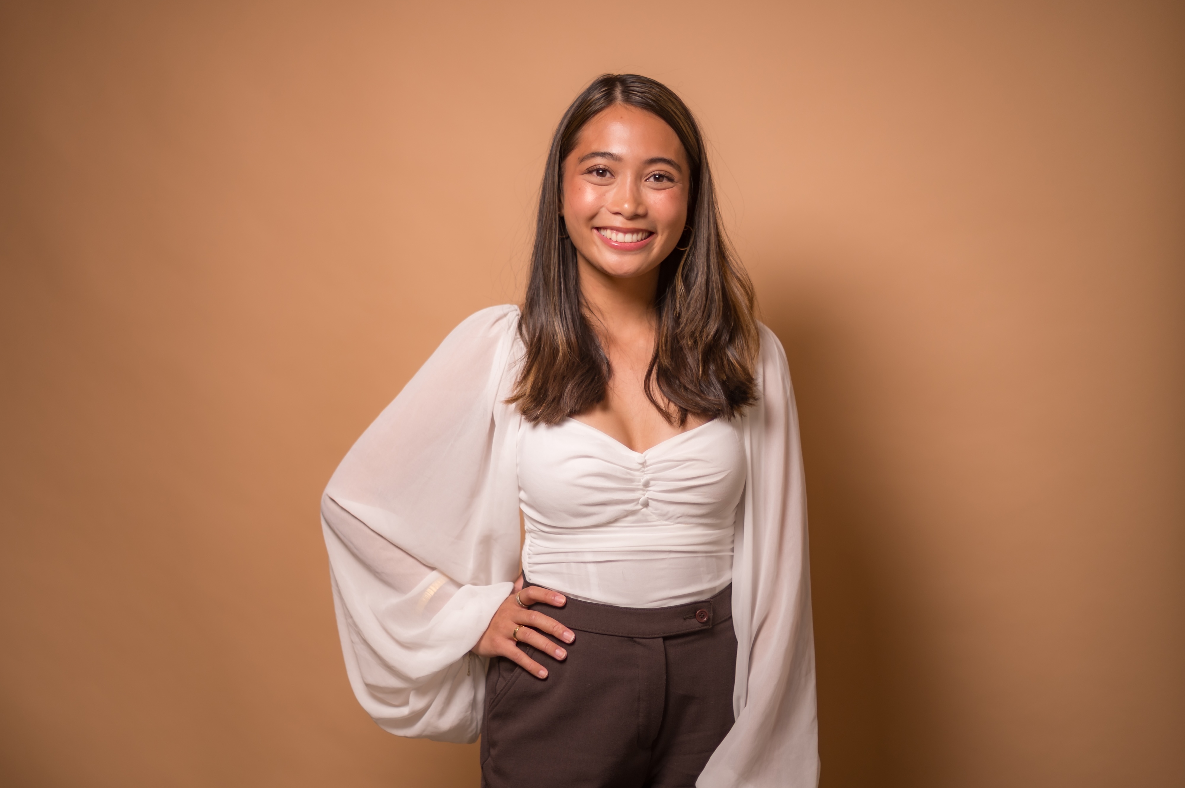 Photo of a student posing in front of a tan background.